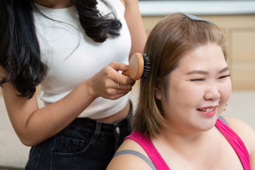 Two friends engage in a beauty session, highlighting the joy of friendship as one styles the other's hair, capturing a playful, relaxed atmosphere.