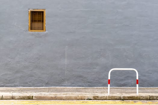 A dark gray wall with a small window in a metal frame, minimalist composition