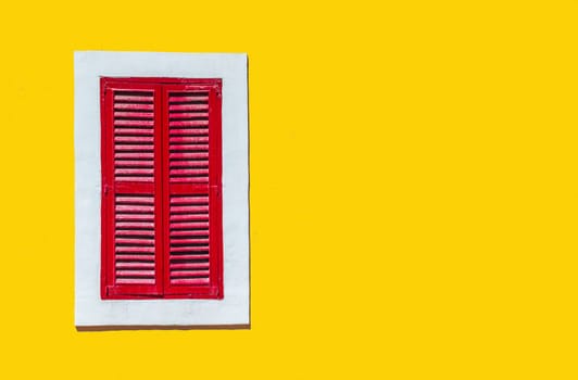 Minimalist style photo of yellow wall with red window in white frame, Murano, Venice, Italy