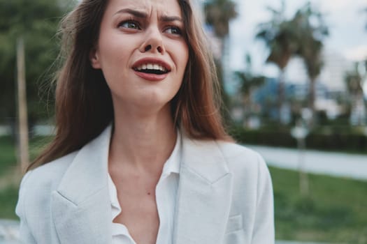 A businesswoman showcasing her ambition and positivity in a professional setting. Dressed in a light-colored suit, her expression radiates confidence amidst nature.
