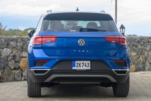 Gaziveren Cyprus -10.04.2025 A vibrant blue SUV stands proudly by a sturdy stone wall, showcasing its modern design against a backdrop of soft clouds. The quiet surroundings enhance its striking appearance.