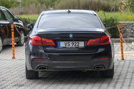 Gaziveren Cyprus -10.04.2025 A stylish luxury sedan is parked peacefully, its polished exterior reflecting the sunlight. The serene natural surroundings create a calm atmosphere, inviting admiration.