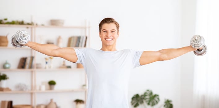 Healthy lifestyle and strength training. Strong man raises dumbbells in interior of living room, free space