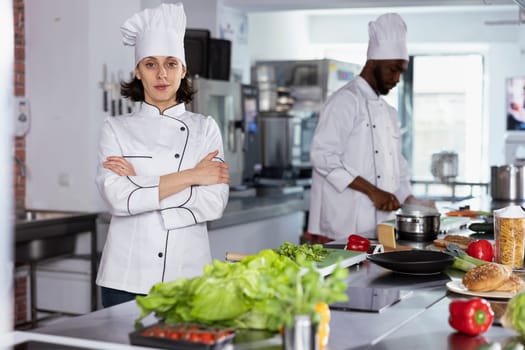 In a luxurious restaurant kitchen, female chef cooking tasty fine dining meals by preparing ingredients using stainless steel tools at the kitchen counter. Mastering food prep techniques.