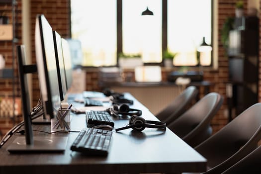 Empty workspace, with no person present, highlighting a modern business setting with desktop monitors. Multiple computers are neatly organized on desks in vacant brick wall office.