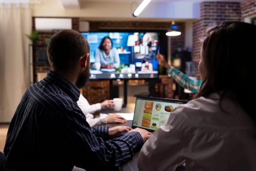 Diverse professionals engaged in a video conference, sharing marketing strategies and financial planning. Late night teamwork and group discussions during virtual meeting in modern workspace.