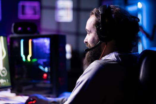 Player reaching final mission in coop FPS videogame, battling flying robots with online friends, using headphones. Gamer wearing headset playing game, fighting final boss helped by teammates