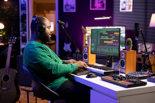 Sound designer pressing keys of electronic midi controller and composing new track, adjusting volume levels on pre amp knobs. Artist producing music on piano synthesizer, mixing sounds.