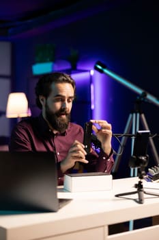 Tech expert assessing smartphone performance, talking about components used inside, doing unboxing video. Entertainer unpacking mobile phone to review it on technology online channel