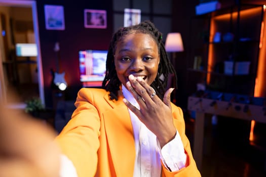 Cheerful girl excited to film in living room used as professional studio for recording vlogs for online channel. Happy teenager in apartment delighted to discuss topics with fans