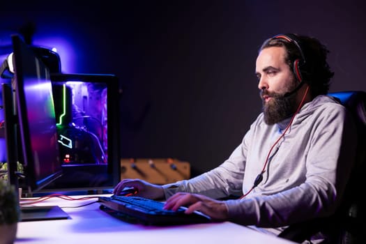Esports player playing videogames in front of subscribers during livestream, providing commentary during gameplay. Professional gamer streaming game in dark studio, entertaining audience
