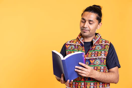 Smiling reading lover delighted to read book from favorite author, enjoying plot, isolated over studio background. Merry person satisfied by good written novel, enjoying leisure time, appreciating literature