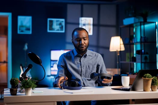 Entertaining content creator in studio films headphones comparison video review for tech enthusiasts. Viral online star hosts technology internet show, unboxing music listening devices