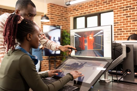 African american coworkers discussing innovative ideas at office desk, using graphic software for website development. Black male manager points to screen, explaining digital tools to female employee.