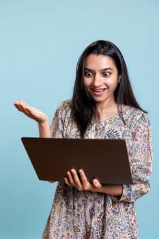Cheerful person gossiping with friends on a video conference call, posing against studio background. Happy relaxed woman bonding with her girls, attend online video call on laptop.