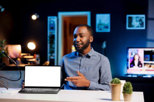 African american man filming himself watching internet videos on mockup laptop requested by viewers. Online influencer reacting to online clips sent by subscribers using isolated screen notebook