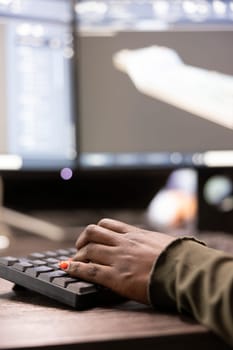 Closeup of african american person typing, inputting data into computer, improving geometry of digital machinery tool. Selective focus of black individual using keyboard and working on a cad software.