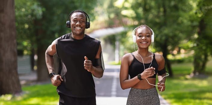Couples Active Leisure. Cheerful Black Guy And Girl Jogging In Summer Park Together, Enjoying Healthy Lifestyle, Smiling At Camera