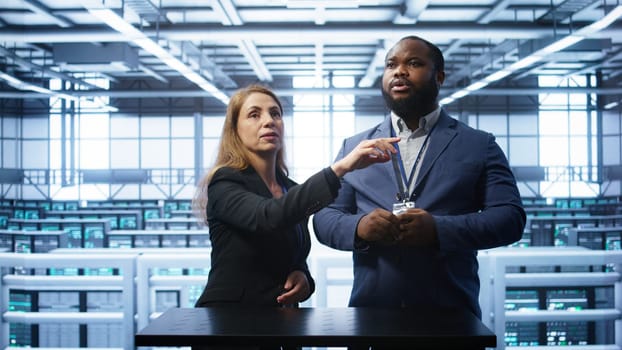 Admin and coworker looking at holograms in data center, doing swiping motions hand gestures. IT support staff members interacting with augmented reality AI visualization in server hub, camera B