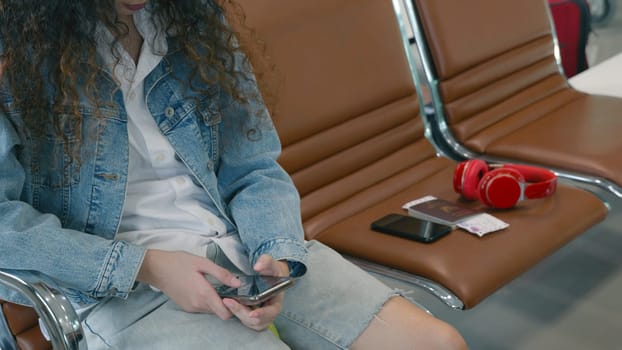 Passenger traveler woman in airport gate play smartphone for waiting air vacation travel, hipster female sitting and using mobile phone in terminal hall area while waiting for her traveling flight