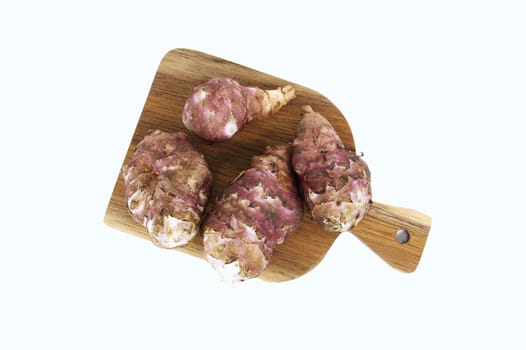 A stack of fresh Jerusalem artichokes displayed on a rustic wooden cutting board against a white background. Perfect for culinary uses, highlighting their earthy texture and natural aesthetics