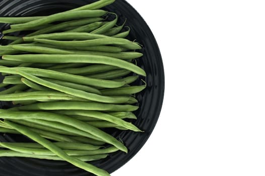 Fresh and vibrant green beans arranged neatly on a black plate, creating a visually appealing contrast and suggesting a healthy and delicious meal preparation