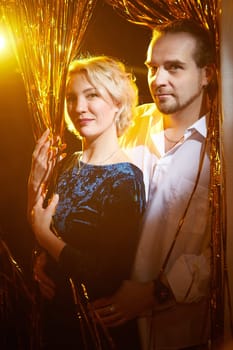 A cheerful couple enjoys the holiday spirit surrounded by bright decorations and warm lights, celebrating the New Year together.