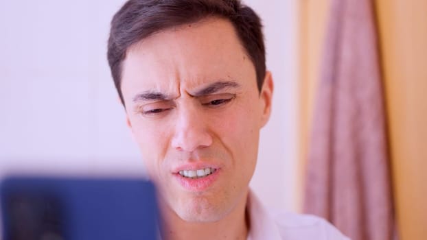 Office worker feeling worried while reading bad news on his mobile phone