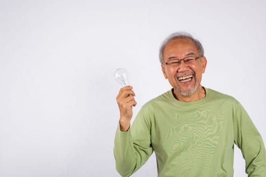 Portrait Asian old man is holding light bulb and smiling studio shot isolated on white background. Concept of intelligence and creativity, as the man is holding a symbol of innovation. Thinking idea