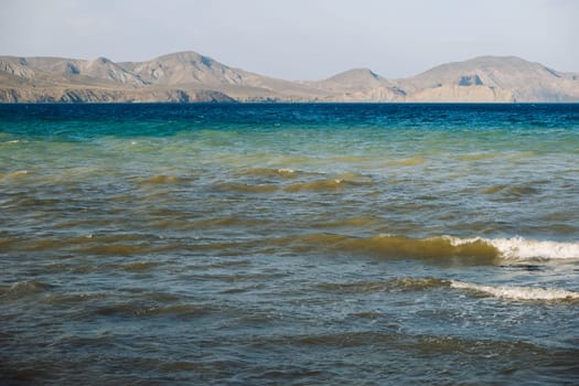 Waves gently lapping the shore in Crimea with mountains in the background