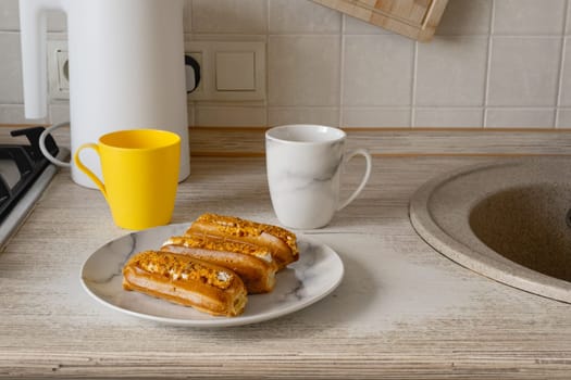 Freshly baked pastries sit in their packaging on a kitchen counter, accompanied by two colorful cups and a plate, creating a cozy morning atmosphere.