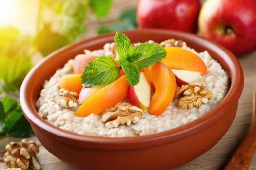 A delicious bowl of oatmeal topped with sliced apples and peaches, garnished with mint leaves.