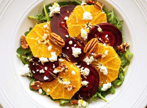 A vibrant salad featuring fresh arugula, slices of orange and beet, crumbled goat cheese, and crunchy pecans. Perfect for a healthy meal or side dish during lunch or dinner.