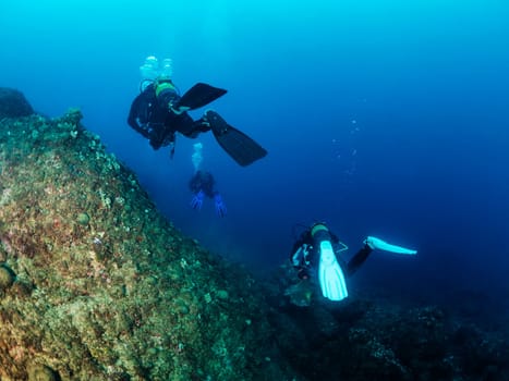 group of scuba divers diving into the blue ocean, concept of active leisure lifestyle and underwater adventure, copyspace for text