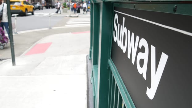 New York City, United States - 29 Aug 2023: Subway sign, underground metro station. Metropolitan entrance fence, public passenger transport exit, yellow taxi cab. Pedestrians people, Manhattan street.