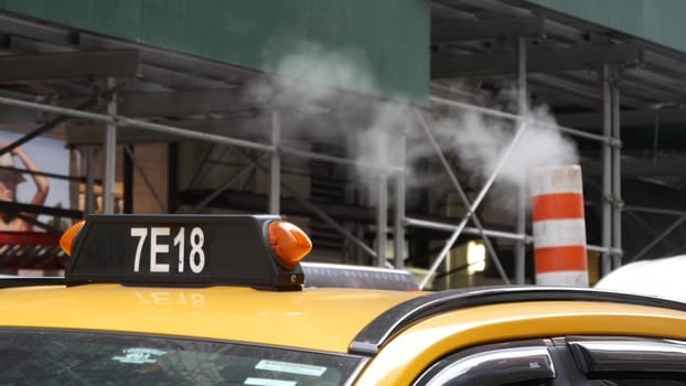 New York City, United States - 8 Sept 2023: Steam vapor vented on street, orange tube stack. Hot smoke pipe. Con Edisons Steam Operations system, Manhattan 5 Fifth avenue. Yellow taxi cab, scaffolding