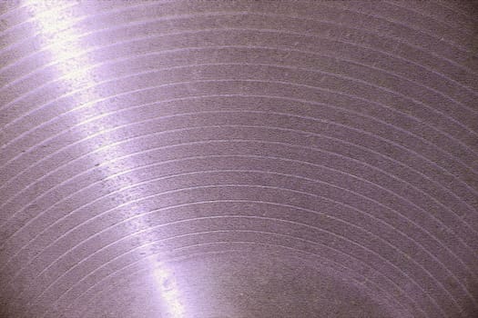 Light is reflecting on a textured purple surface creating concentric circles, suggesting a sense of depth and movement