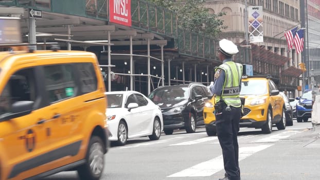 New York City, United States - 29 Aug 2023: Manhattan Midtown 34 street, Madison avenue crossroad intersection. Urban road in USA. Traffic Control Police guard or NYPD flagger. Yellow taxi car, people