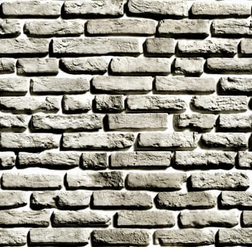 Gray brick wall creating a textured background with visible light and shadow effects