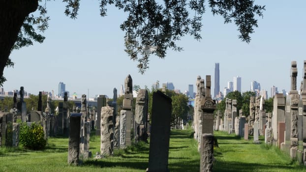 New York City, United States - 14 Sept 2023: Calvary cemetery in Queens, USA. Manhattan Downtown urban skyline cityscape architecture. Tombstones on graves, huge graveyard. Large cemetry grass lawn.