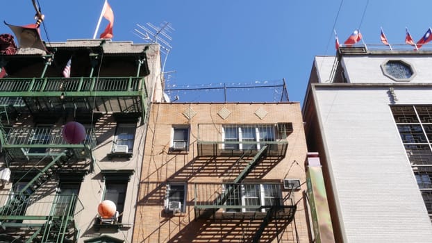 New York City, United States - 14 Sept 2023: Manhattan Chinatown Mott street, chinese ethnic district buildings architecture, USA. Flags on chinese community center in little China. Fire escape ladder