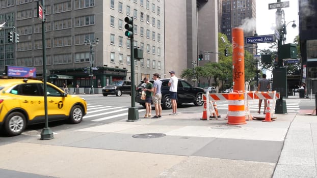 New York City, United States - 4 Sept 2023: Manhattan Midtown East 42 street, 2 avenue crossroad intersection. Urban road car traffic in USA. People, pedestrians on zebra. Yellow taxi cab. Smoke stack