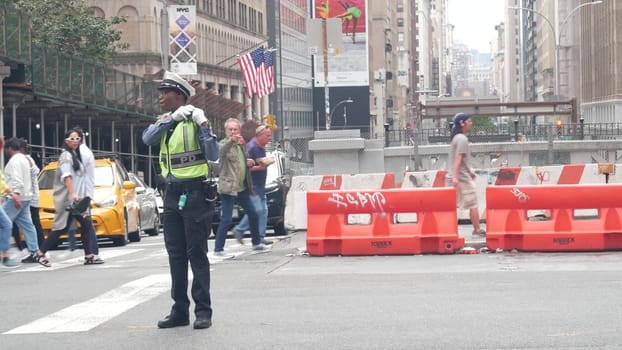 New York City, United States - 29 Aug 2023: Manhattan Midtown 34 street, Madison avenue crossroad intersection. Urban road in USA. Traffic Control Police guard or NYPD flagger. Yellow taxi car, people