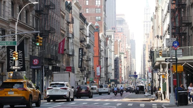 New York City, United States - 8 Sept 2023: Manhattan Soho District, Broadway street perspective. Urban road car traffic, yellow taxi, people. USA building architecture, Fashion stores for shopping.