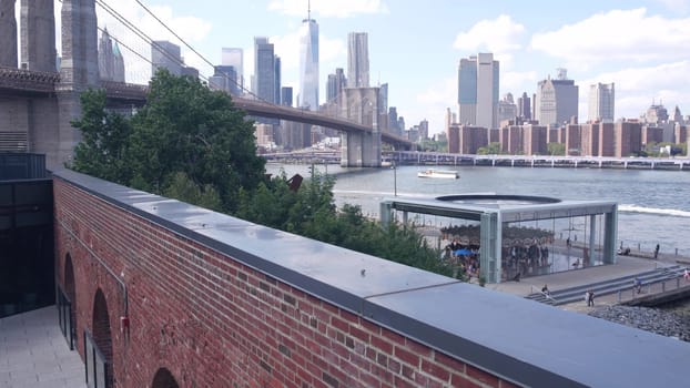New York City, United States - 30 Aug 2023: Manhattan downtown skyline, waterfront cityscape from Time Out Market. Riverfront Carousel in Dumbo near Brooklyn Bridge. World Trade Center skyscraper.
