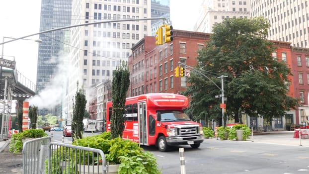 New York City, United States - 9 Sept 2023: Manhattan Downtown Financial District Water street crossroad intersection. USA. Urban road car traffic. Red bus, people. Hot smoke stack, steam pipe.