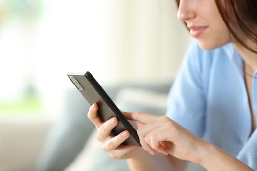 Close up of a woman hand using phone sitting on a couch at home