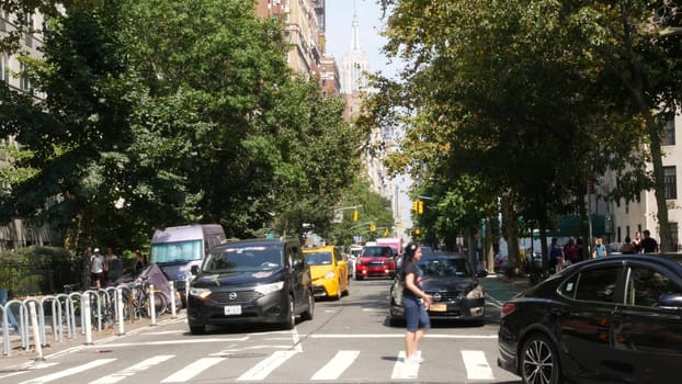 New York City, United States - 8 Sept 2023: Manhattan Greenwich Village street, 5th Fifth 5 avenue near Washington Square Park. American road car traffic, people. Yellow taxi cab, USA. Trees greenery.