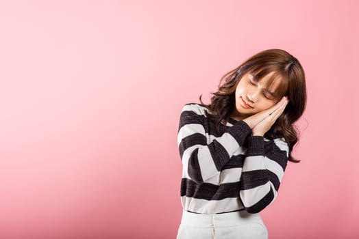 Portrait Asian beautiful young woman pretended emotions sleeping tired eyes closed dreaming with hands together near face, studio shot on pink background, with copy space, insomnia concept, copy space