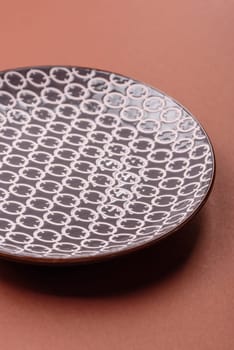 Empty ceramic plate on a monochrome brown background. Empty plate with cutlery on a dining table
